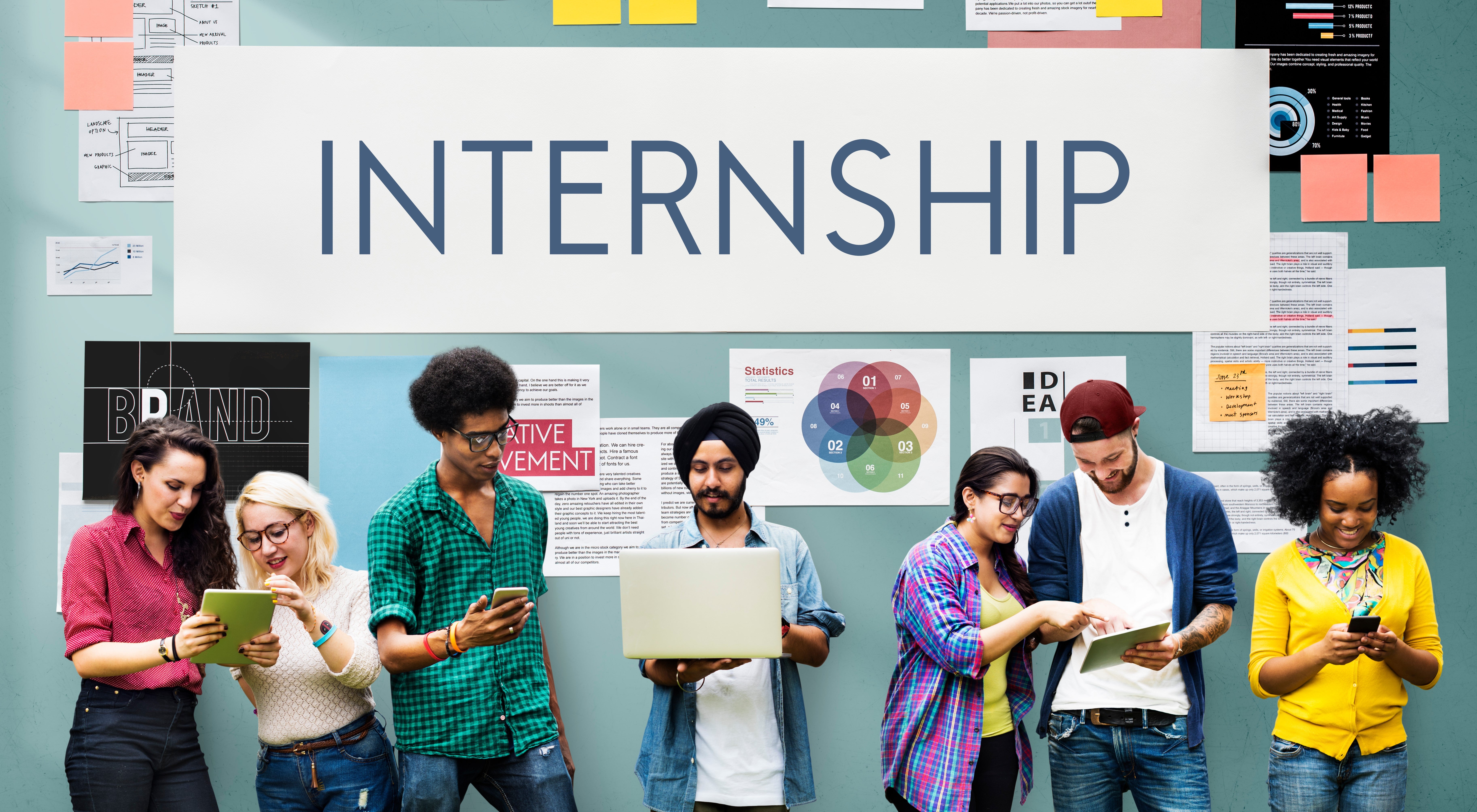 Students standing in front a wall that has a sign Internships